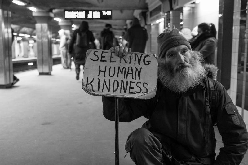 homeless man holding up sign that says 