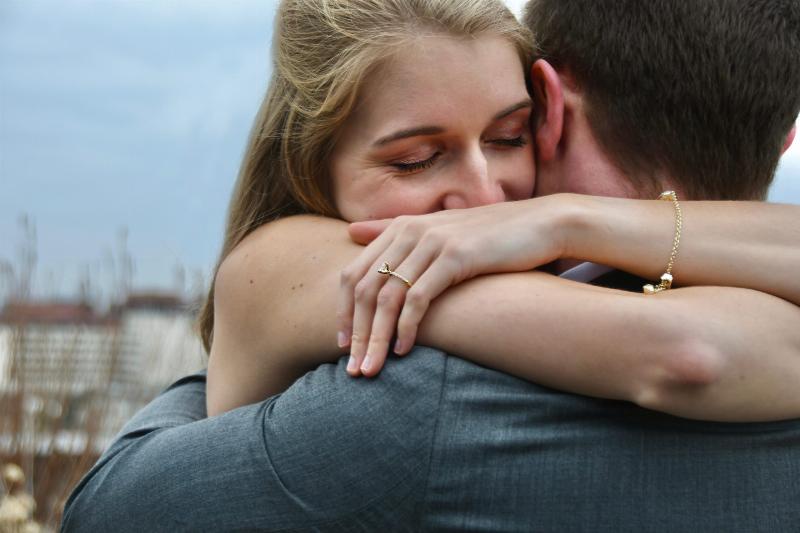 woman hugs man tightly with eyes closed