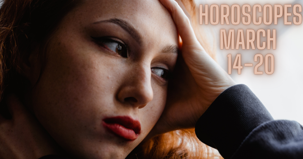 woman rests her elbow on window sill and her hand on her forehead while deep in thought