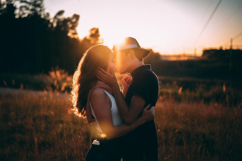 man and woman about to kiss under sunlight in a field