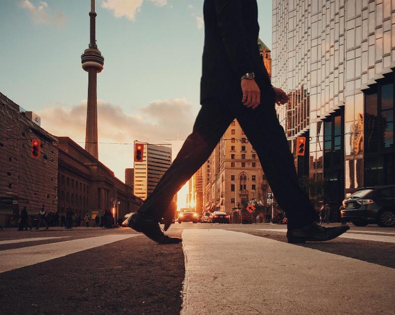 man in a suit crossing street  by the CN tower