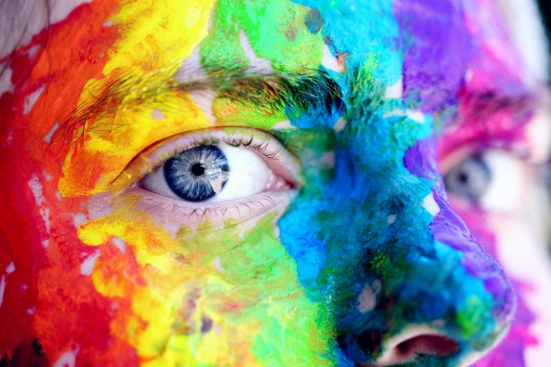 close up of man's face with blue eyes covered in paint
