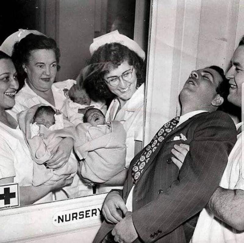 father faints in front of nursey with nurses holding triplets