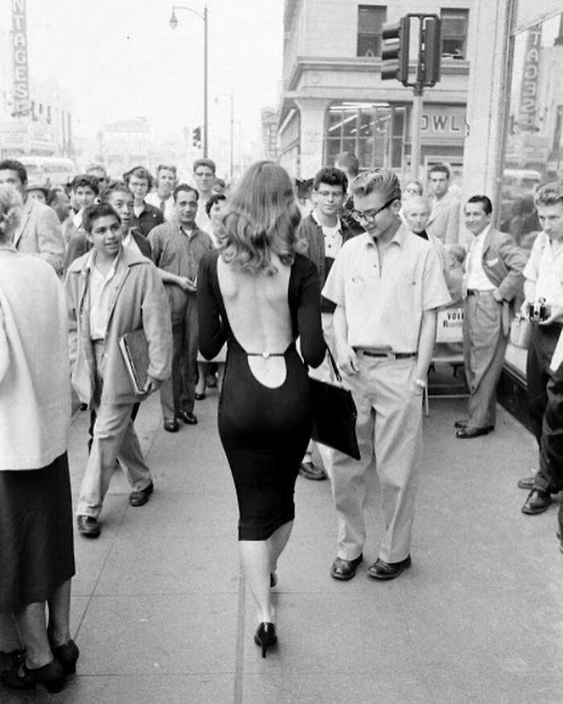 woman walking through staring men in low back dress