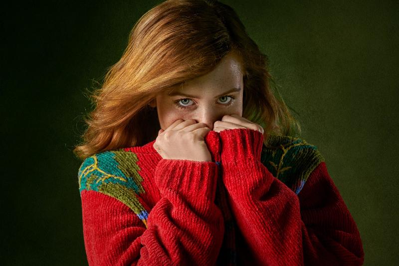 woman hides her face inside red sweater