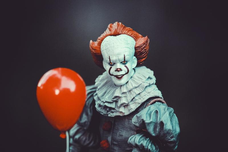 scary clown holding red balloon