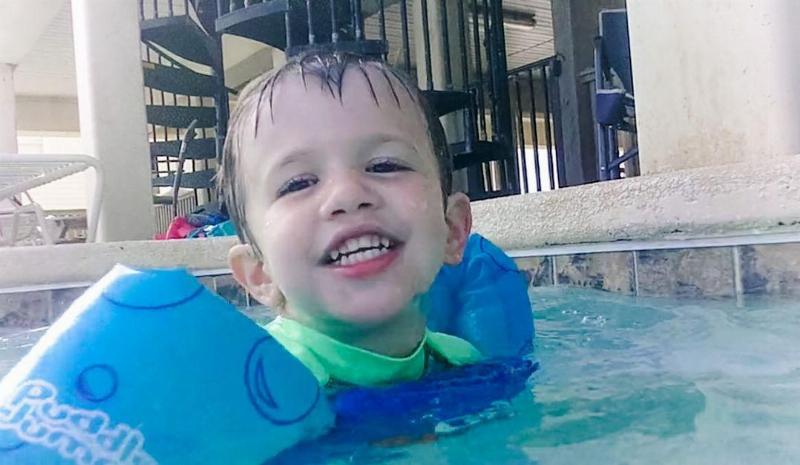 Levi smiling while swimming in the pool with floaties