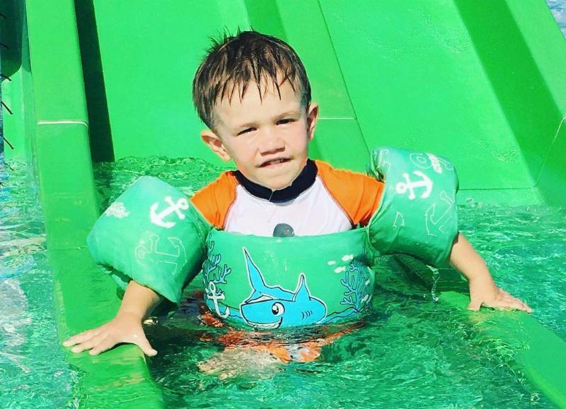 Levi wearing floaties on water slide