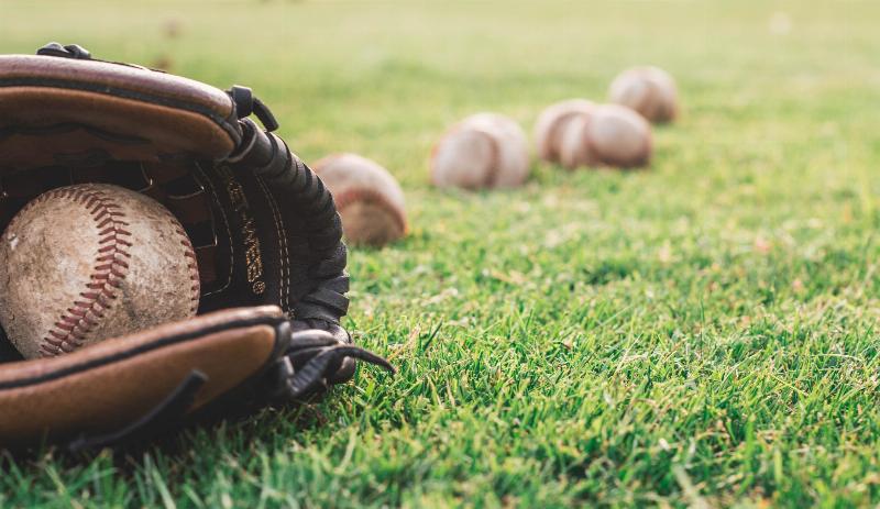 Baseball glove holding balls by other balls on the grass