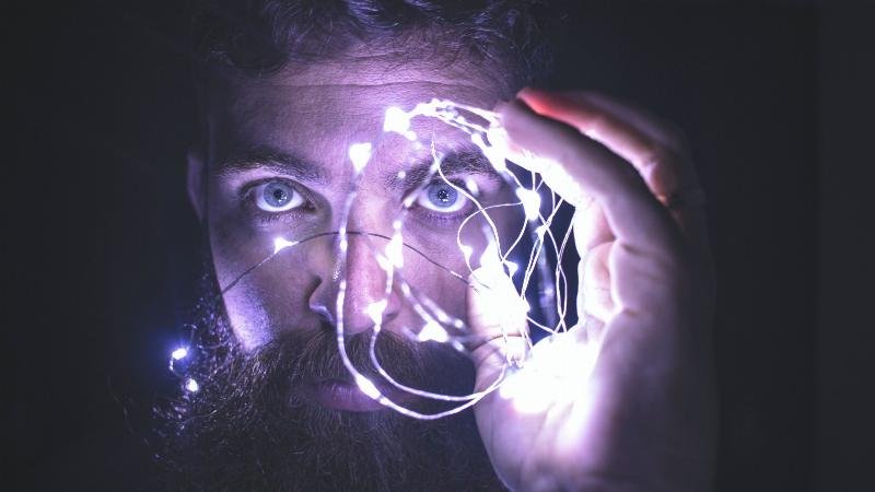 man holding lightstring up to his face