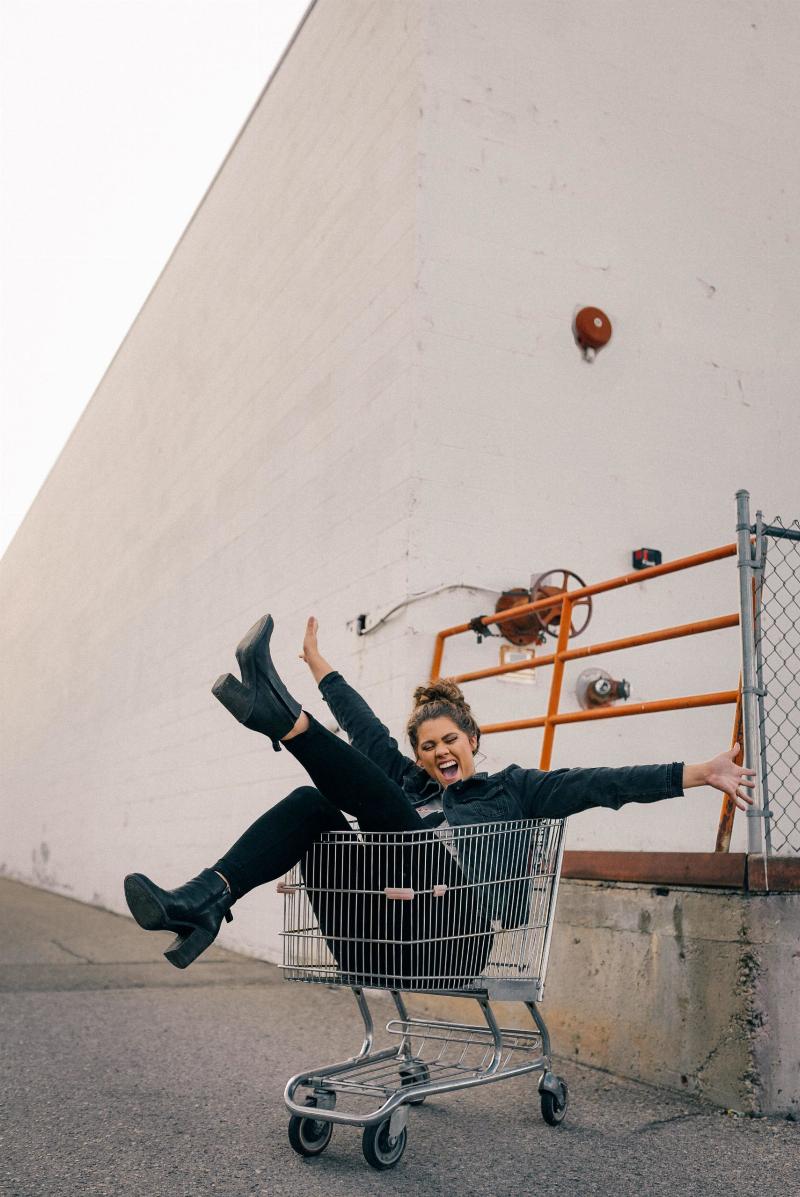 woman sitting in shopping cart with her arms up