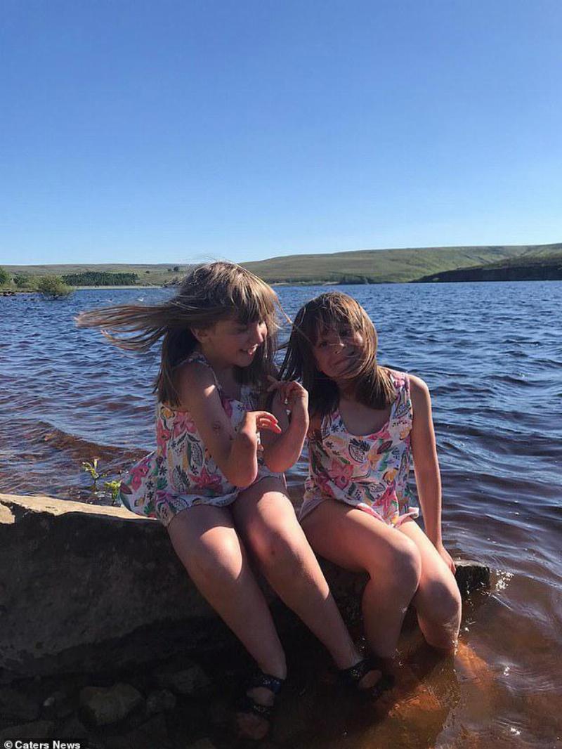 Ben's daughters in matching outfits sitting on a rack by the lake