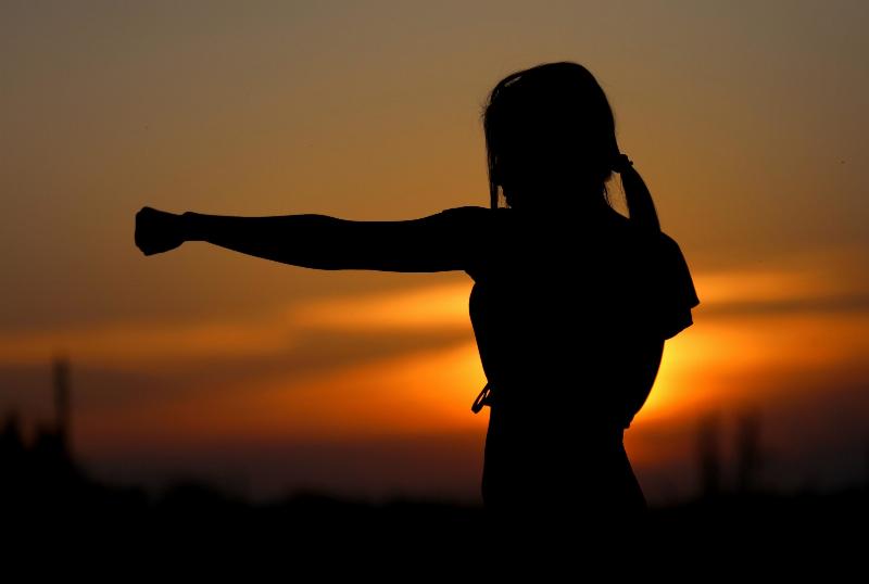 silhouette of woman kickboxing by the sunset