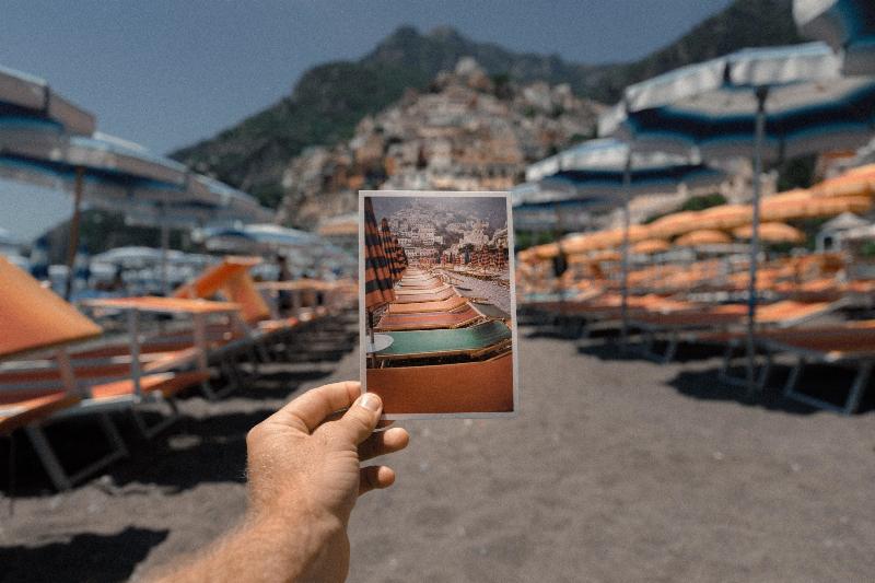Hand holds picture of the beach to the same beach area