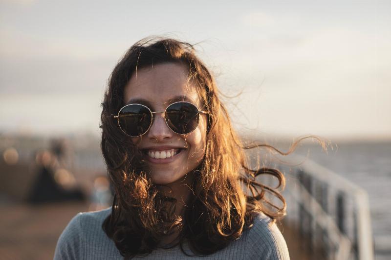 Woman smiling at the pier with her hair blowing