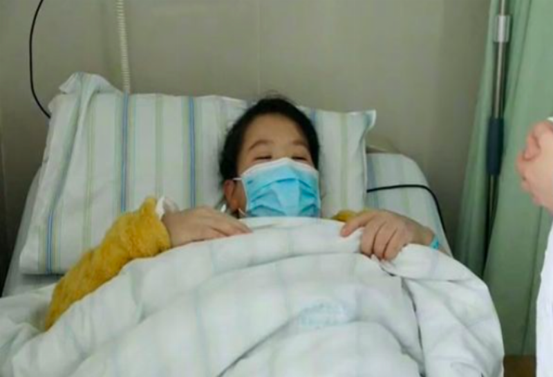 Liu laying in hospital bed with mask on