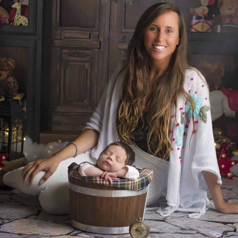 Photoshoot picture of mother with new born baby posing in a barrel