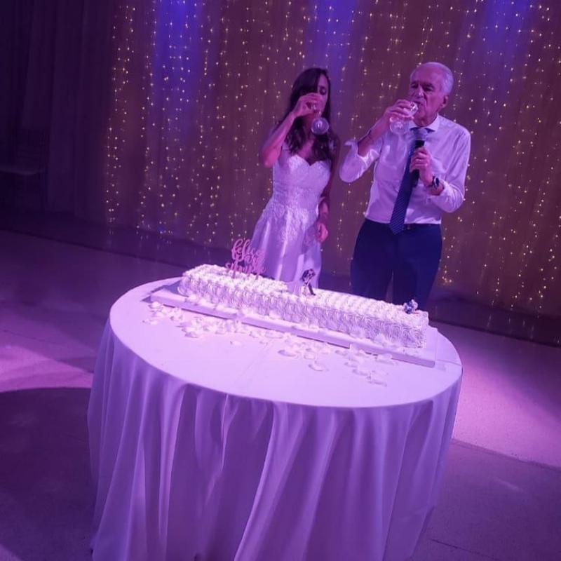 Renee and Alberto at wedding reception having a drink by the cake