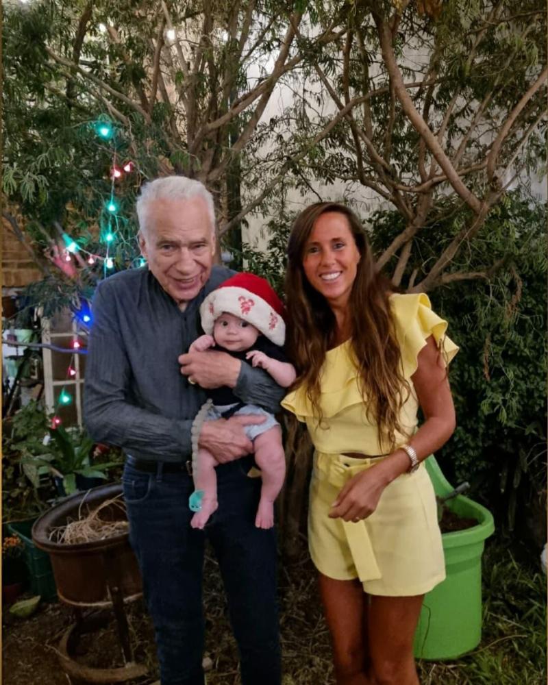 renne and alberto hold baby up for photo at chirstmas