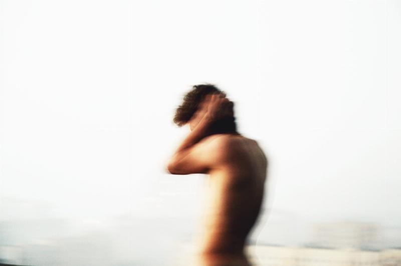 blurry shirtless man blocking his ears with his hands