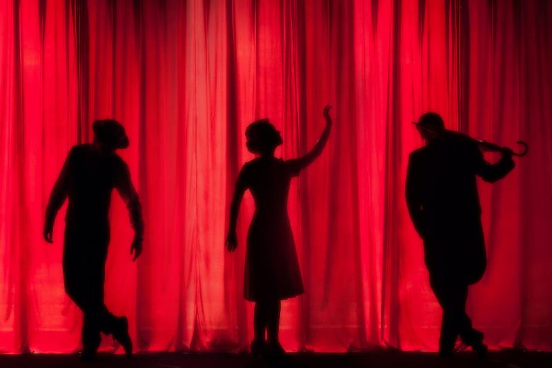 3 silhouettes standing on stage