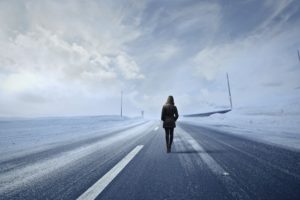 person walking in winter coat on empty snowy street