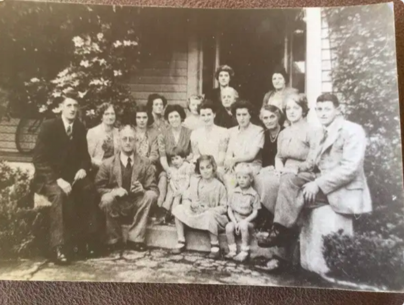 black and white big family photo in front of the house with ghost in the shadows