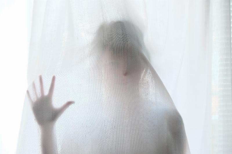 hand on window through curtain of woman who looks like ghost