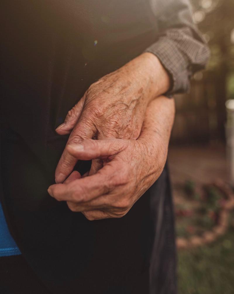 older man and woman hold hands (closeup)