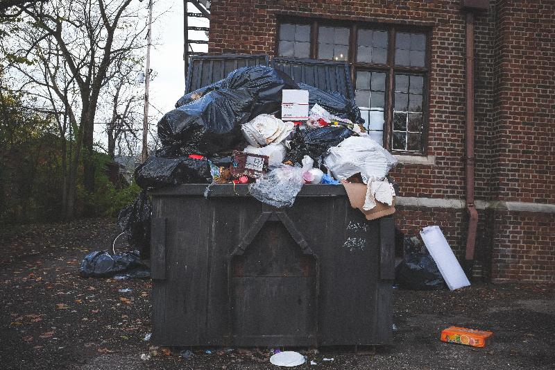 dumpster piled up with trash by redbrick building