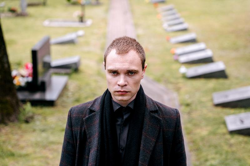 man standing in cemetery with coat on