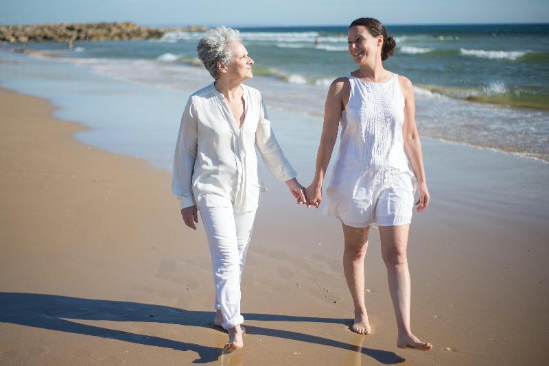 Woman in White Dress Holding the Hand of an Elderly Woman