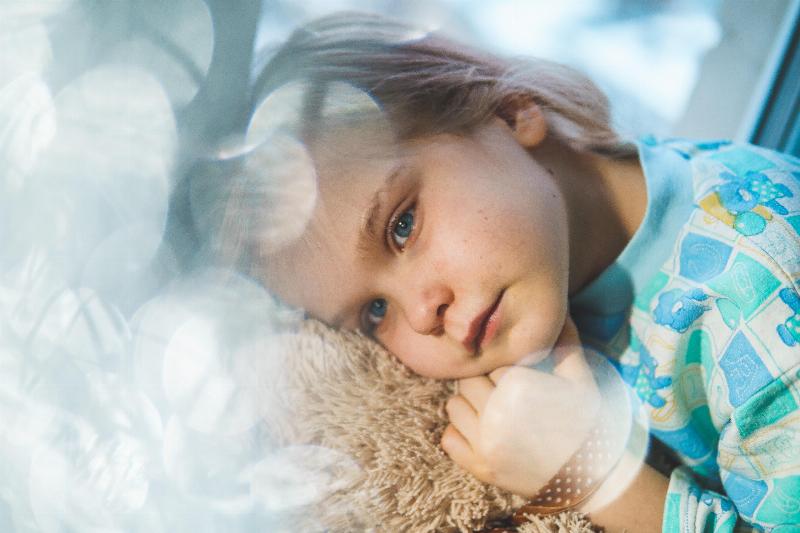 a child with a fever lying with his toy bear