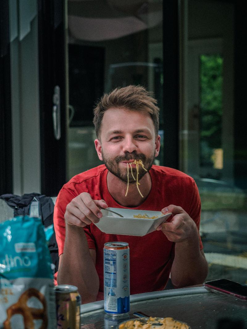 man smiles while eating noodles coming out of his mouth