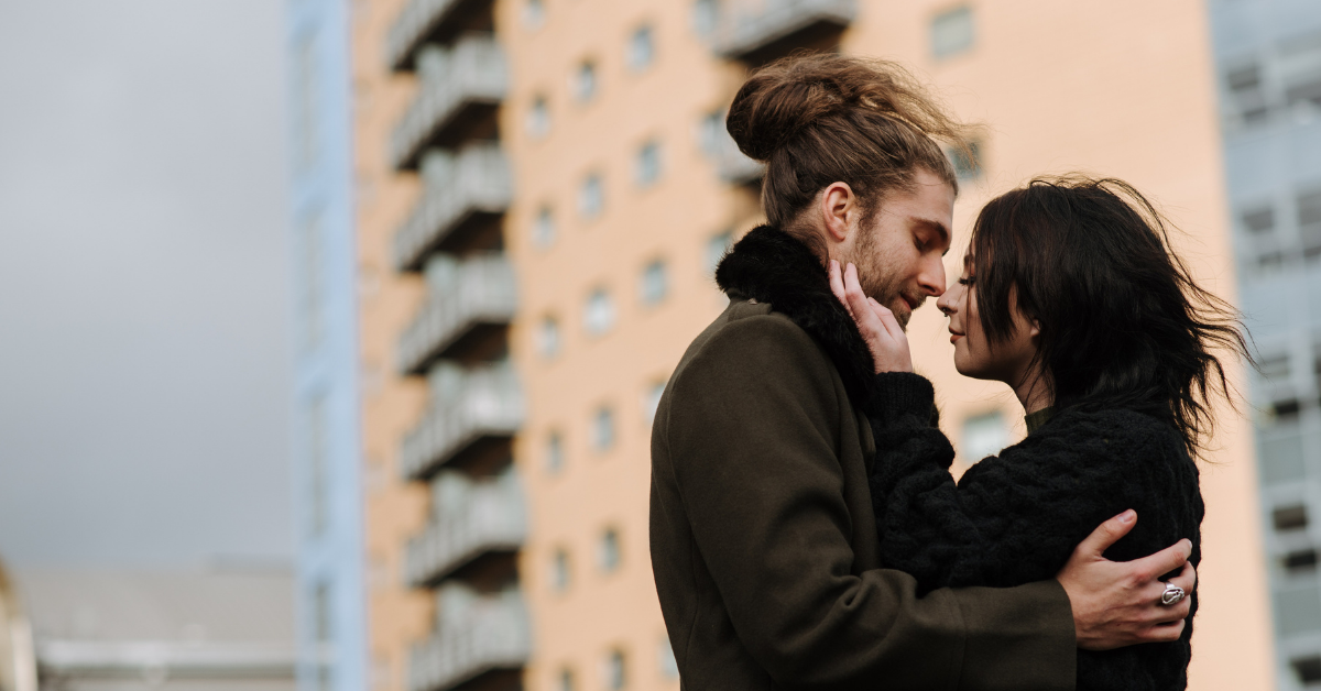 A woman and a man in embrace in front of a building.