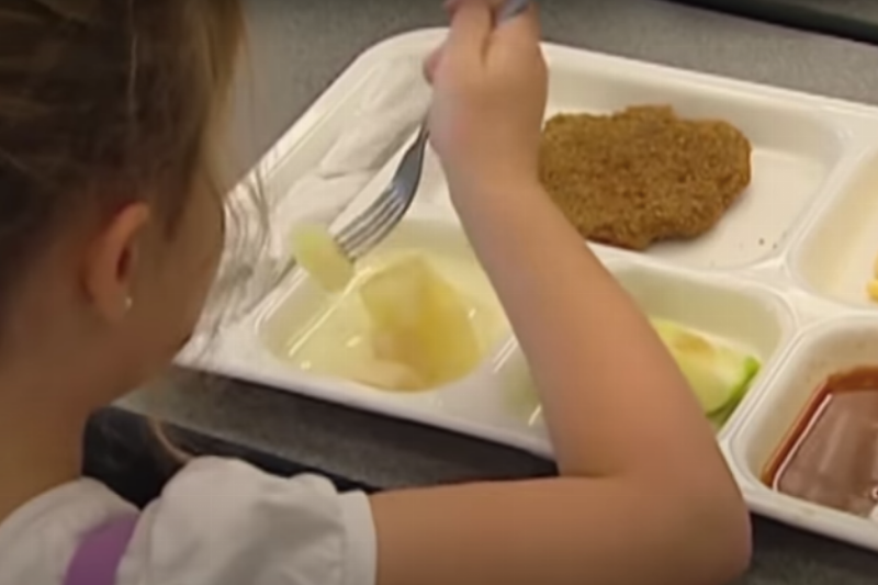 girl eating school lunch from tray