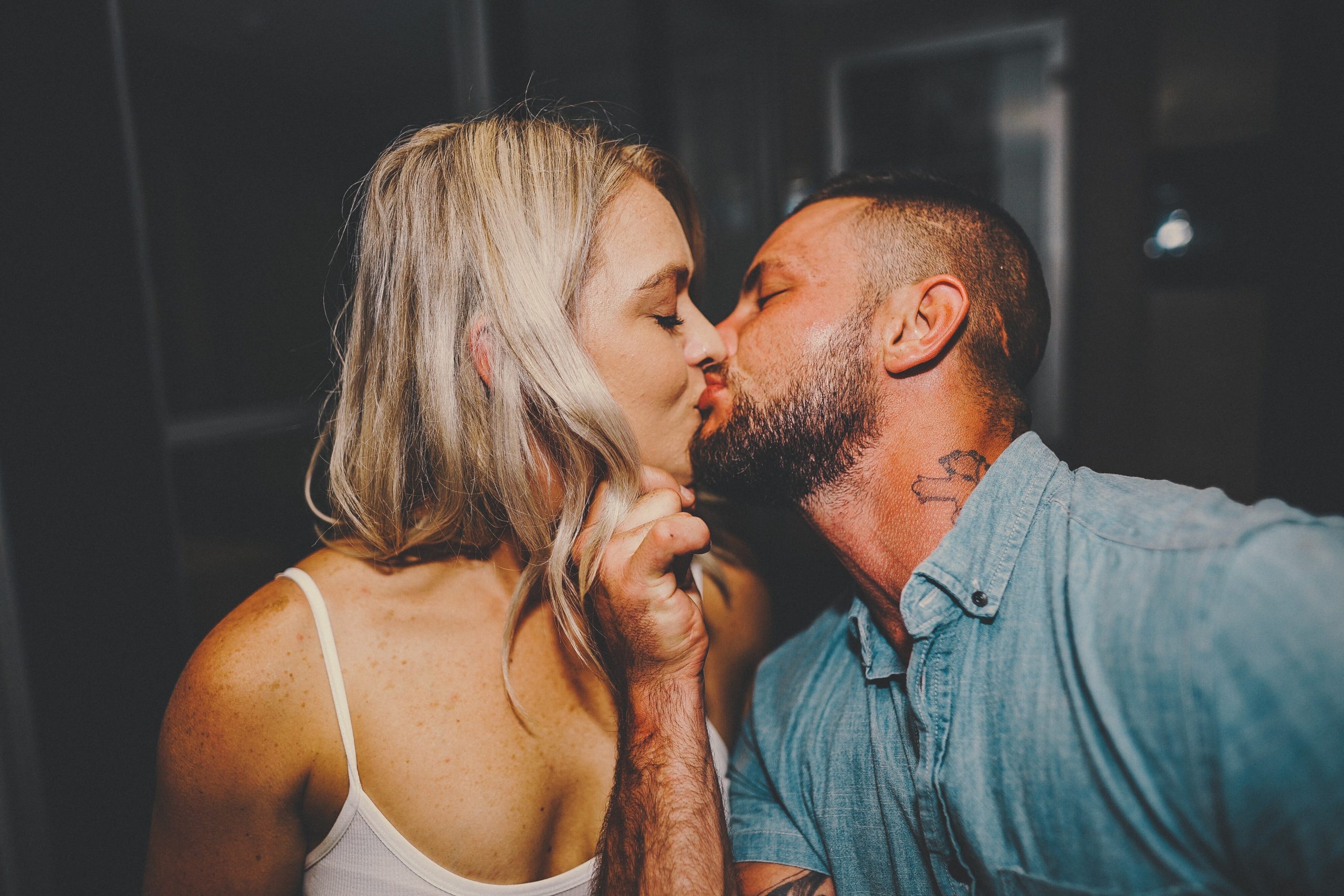 man holds woman's face as they kiss