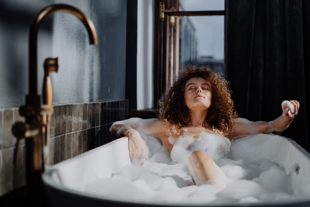 woman laying in bubble bath with eyes closed