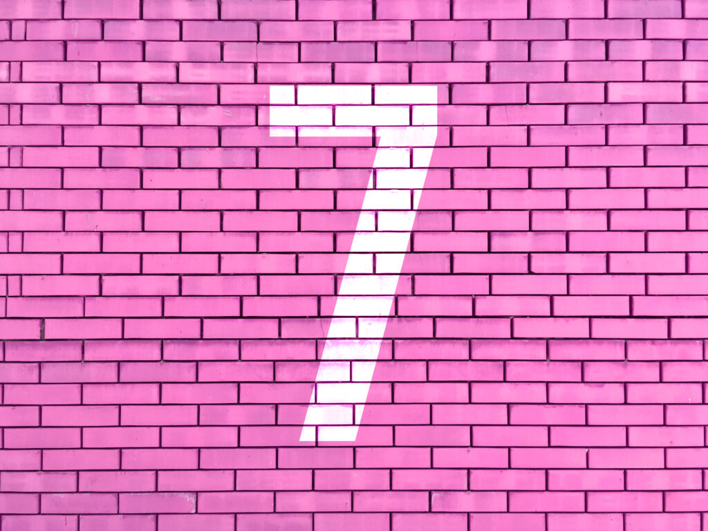 white block number 7 painted on pink brick wall
